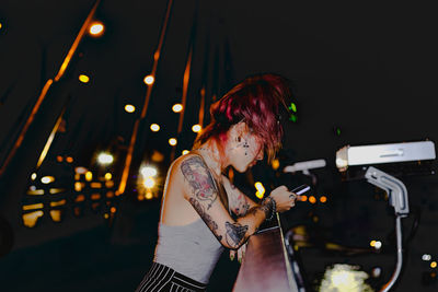 Woman holding illuminated lighting equipment at night