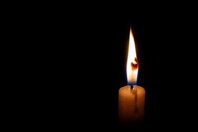 Close-up of illuminated candle in darkroom