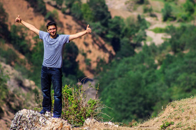 High angle view of young man with arms outstretched against landscape