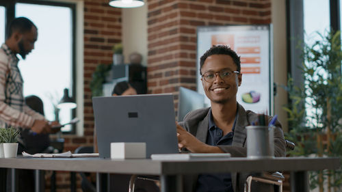 Smiling businessman with laptop at desk
