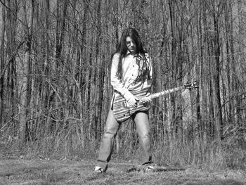Woman playing guitar against trees