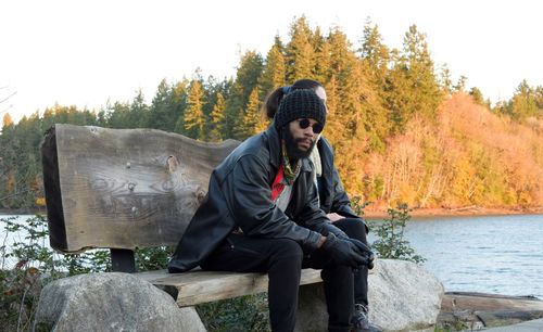 Portrait of man sitting on bench against lake