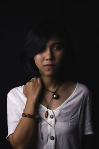 Portrait of young woman against black background