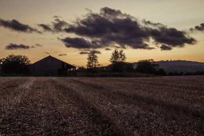 House on field against sky during sunset