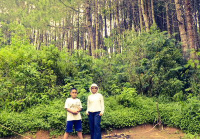 Rear view of people standing by plants in forest