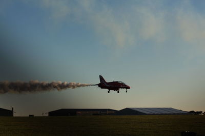 Airplane flying over field against sky