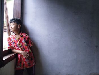 Young woman looking away against wall