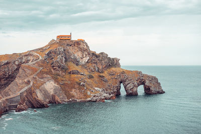 Rock formation by sea against sky