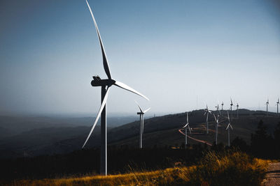 Wind turbines on landscape against clear blue sky