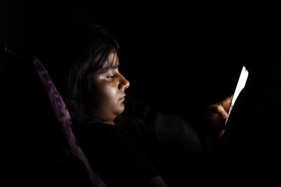 Portrait of mid adult man using smart phone in darkroom