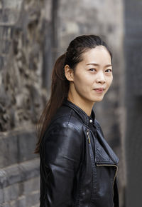 Portrait of woman standing against black background