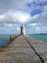 Lighthouse by sea against sky