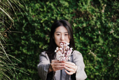 Beautiful chinese asian woman holding almond tree flowers.spring. selective focus on flowers