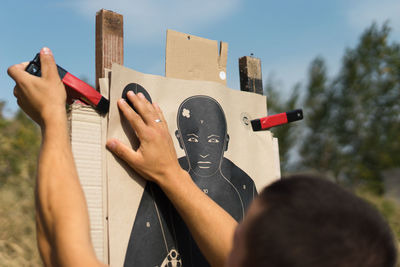 Cropped image of man adjusting clamp on shooting target