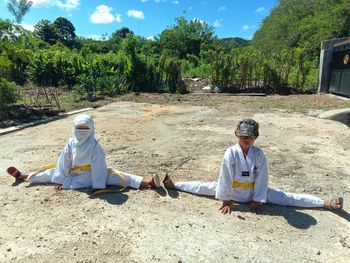 Friends sitting on land against trees