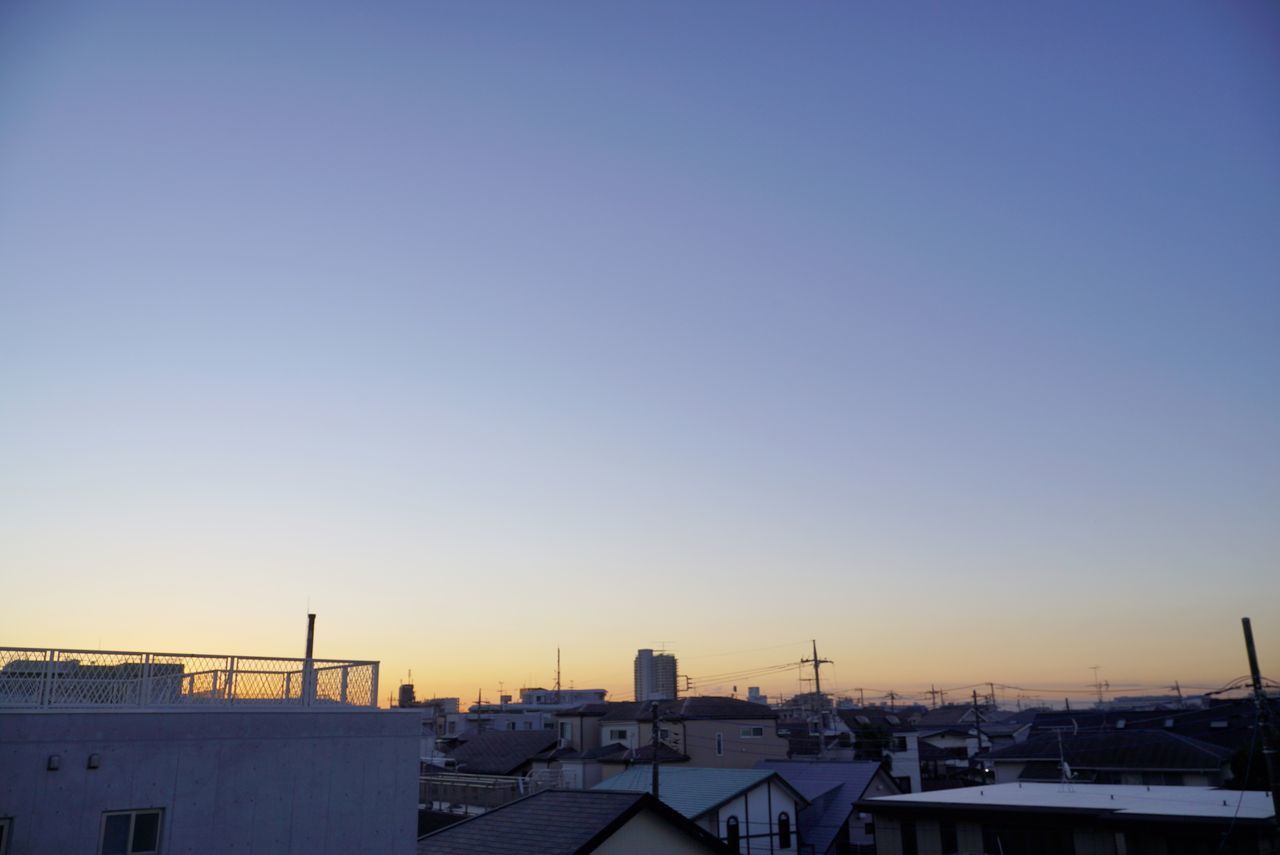 HIGH ANGLE VIEW OF CITYSCAPE AGAINST CLEAR SKY AT SUNSET