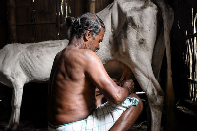 Midsection of shirtless man in stable