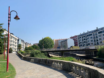 Bridge over canal by buildings against clear blue sky