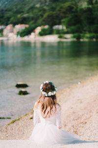 Rear view of woman standing against lake