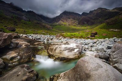 Scenic view of river by mountains against sky