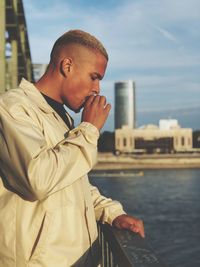 Young man standing in city against sky