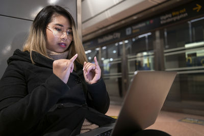 Woman at train station using laptop