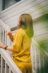 Side view of woman standing by railing