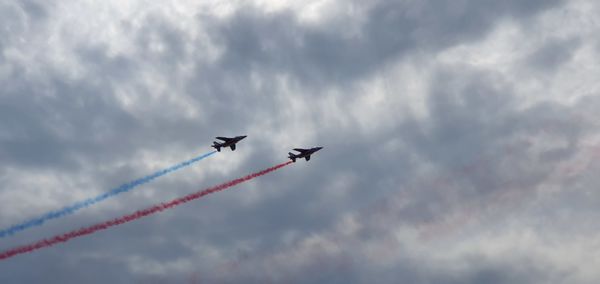 Low angle view of airshow against cloudy sky