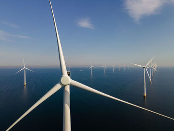 Wind turbines in sea against sky