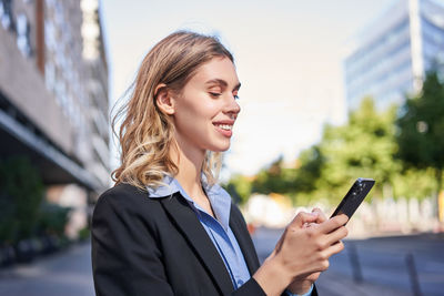 Young woman using mobile phone in city
