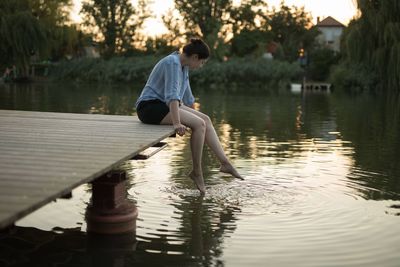 Woman sitting on a pier by the river.