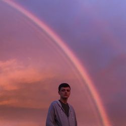Portrait of man standing against rainbow in sky