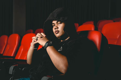 Young man looking away while sitting on chair