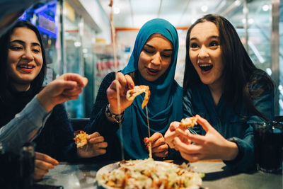 Cheerful female friends eating at cafe