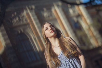 Young woman looking away while standing outdoors