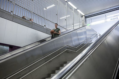 Man with basketball standing on escalator