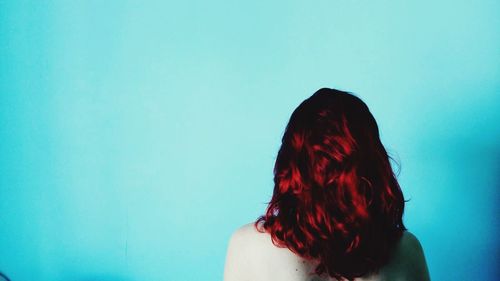 Rear view of woman standing against blue wall