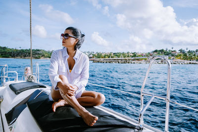 Young man sitting on boat in sea against sky