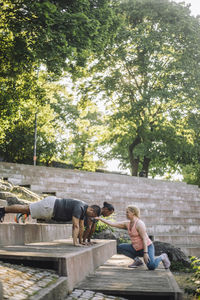 Female coach guiding men practicing push-ups on steps