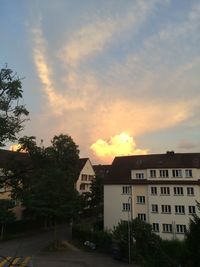 Houses against cloudy sky at sunset