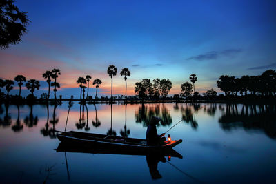 Boats in lake against sky during sunset