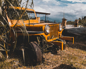 Abandoned train on field against sky