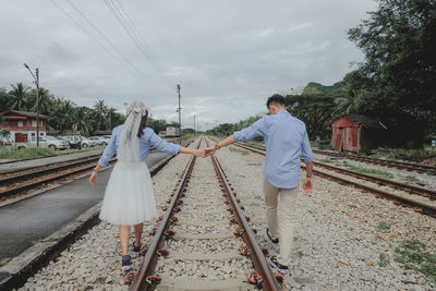 People walking on railroad tracks against sky