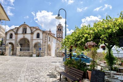 Street amidst trees and buildings against sky