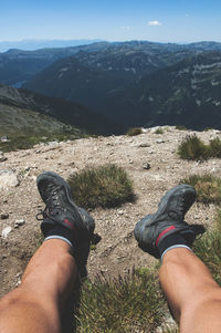 Low section of man on mountain against sky