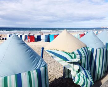 Deck chairs on beach against sky