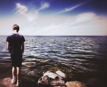 Rear view of man looking at sea against sky