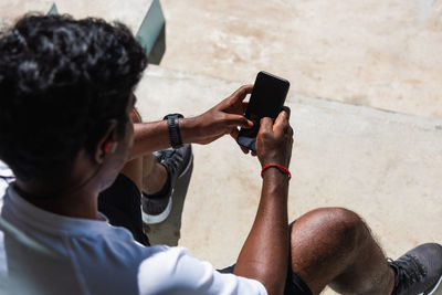 High angle view of man using smart phone while sitting outdoors