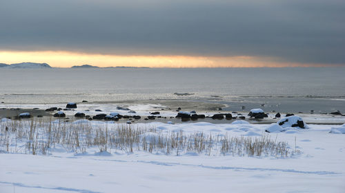 Snow covered landscape against cloudy sky