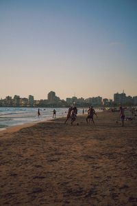 People on beach against clear sky